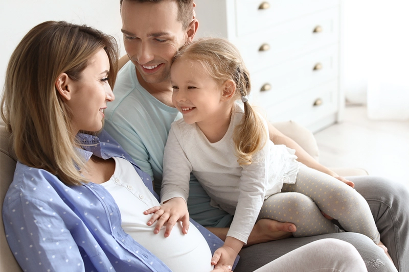 family sitting on couch and excited about possibility of having another child