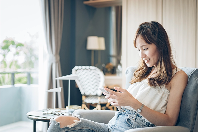 women sitting in living room on her phone tracking ovulation