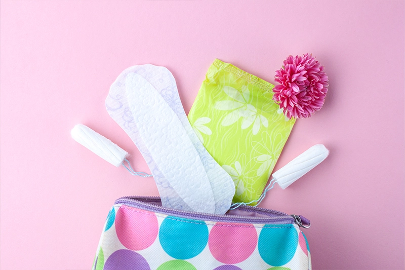 women's purse with contents of tampons, pads, liners falling out on the counter
