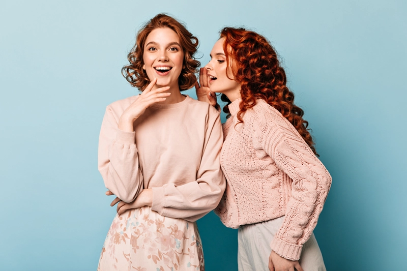 two women whispering and sharing pregnncy confessions with each other